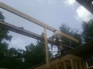 Carpenter setting a ridge beam over a new addition frame — Ice Dam Removal by Roofing Brothers in Mineral City