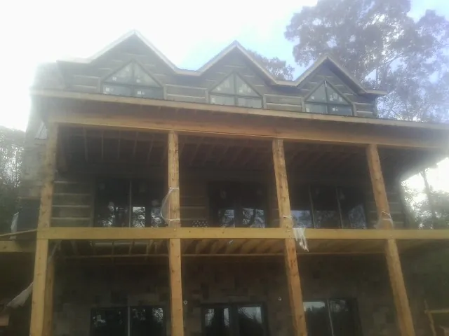 Dormers and porch framing on a large log home under construction — Roof Coating work by our crew in Mineral City