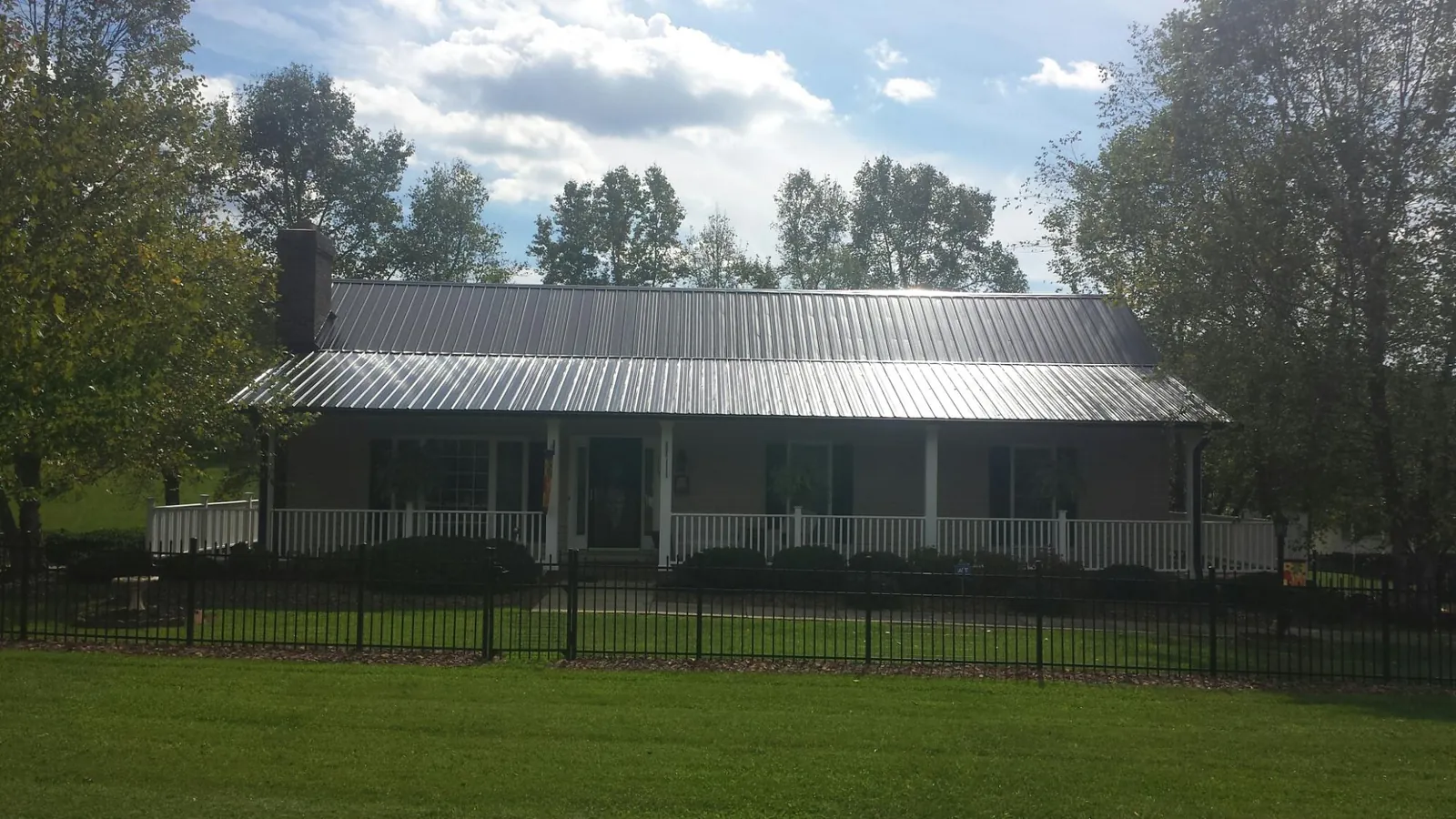 Gray metal roof on a brick ranch with a full width front porch — Gutter Guard Installation work by our crew in Mineral City