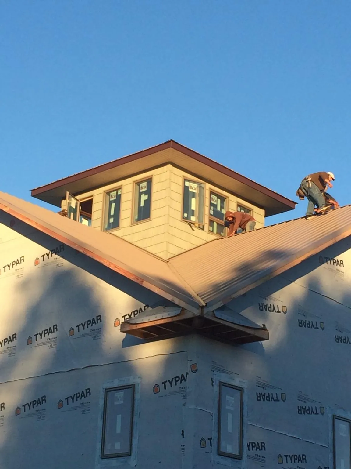 Roofers working around a rooftop cupola on a new metal roof at sunset — Roof Waterproofing in Mineral City by Roofing Brothers
